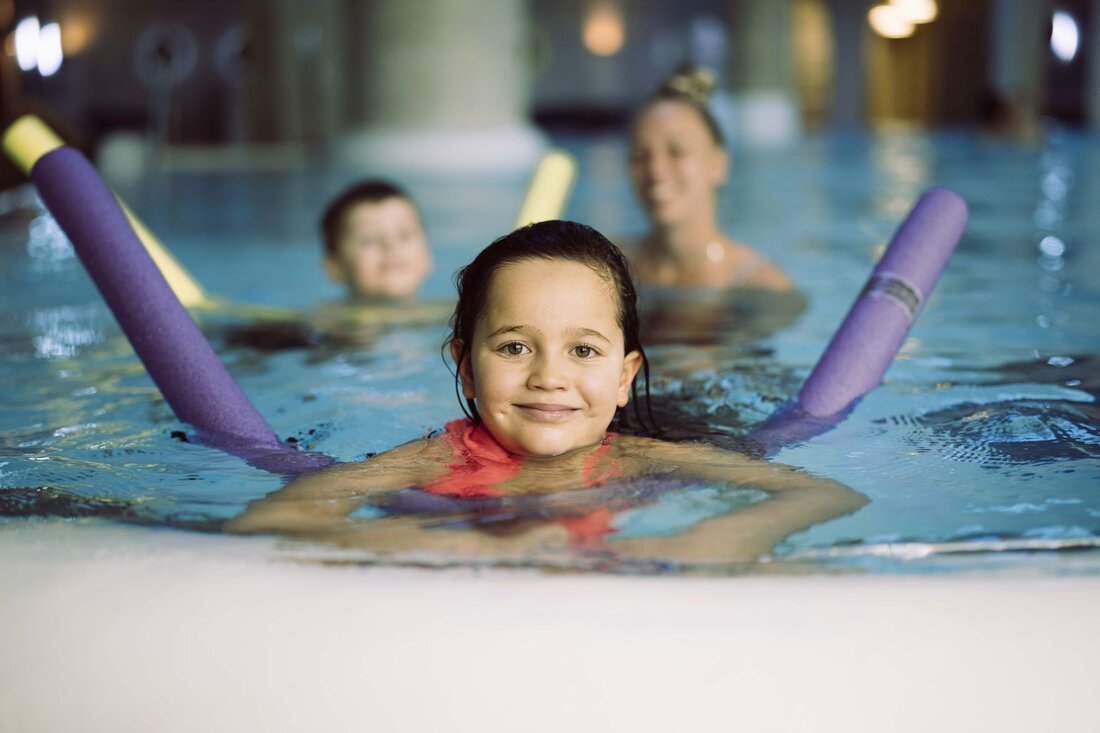 Kind mit Schwimmnudel im Pool